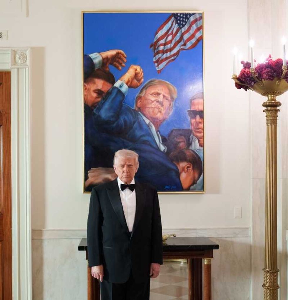 Trump poses with a photo from his assassination attempt after a wave of deadly shootings
