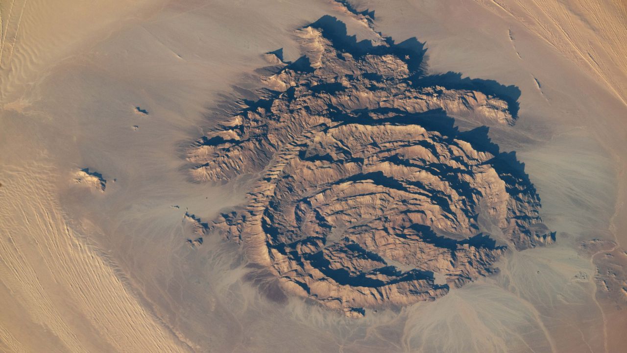 Concentric rocky rings adorned with ancient artwork wear a magma ‘hat’ in the Sahara — Earth from space