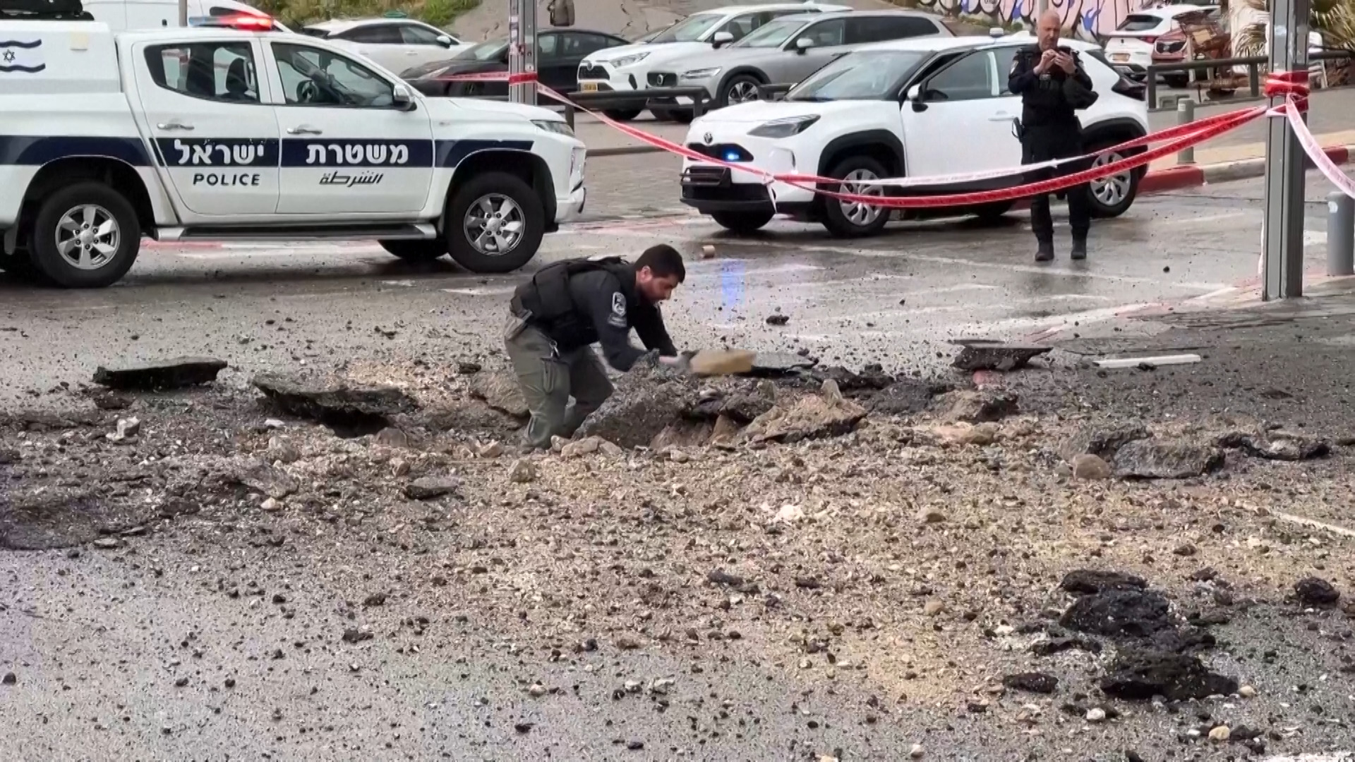 Israeli police inspect damage on the road after missile impact